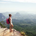 Young,Woman,Traveler,With,Backpack,Standing,On,Top,Of,A