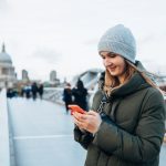 Pretty,Smiling,Woman,In,Hat,And,Coat,Using,Mobile,Phone